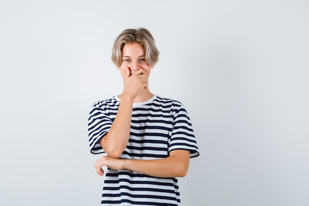 Kostenloses Foto hübscher teenager im gestreiften t-shirt mit der hand auf dem mund und glücklich aussehend, vorderansicht.