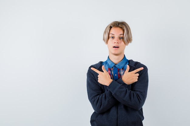 Hübscher Teenager im Hemd, Hoodie, der nach links und rechts zeigt und unentschlossen aussieht, Vorderansicht.