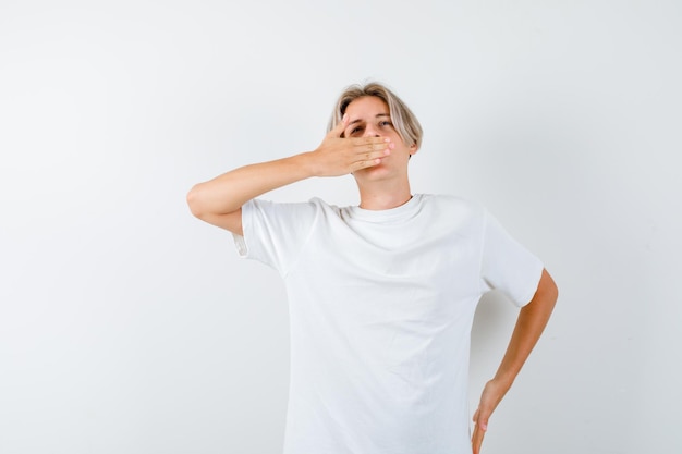 Hübscher Teenager in einem weißen T-Shirt gähnend