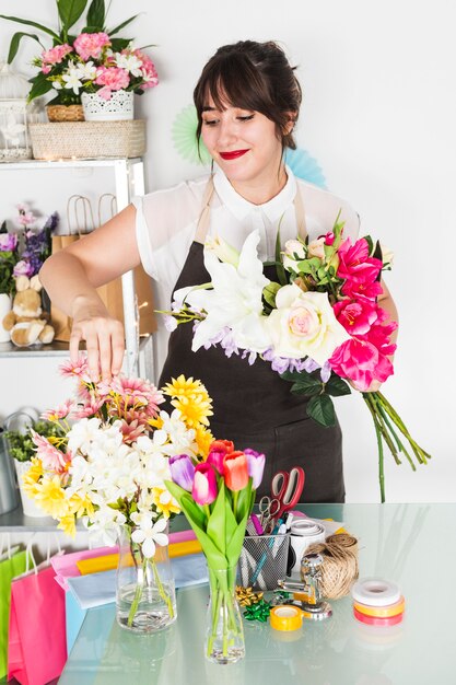 Hübscher weiblicher Florist, der Blumen im Vase anordnet