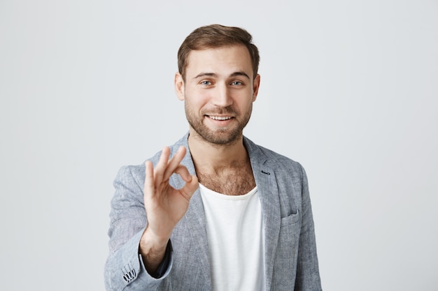 Hübscher zufriedener bärtiger Mann zeigen okay Zeichen