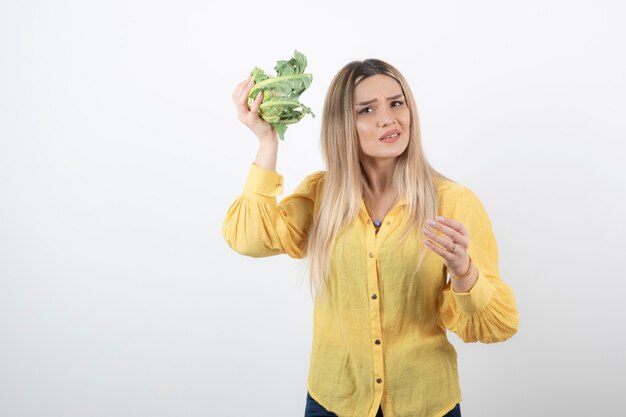 hübsches Frauenmodell, das Blumenkohl in der Hand steht und hält.