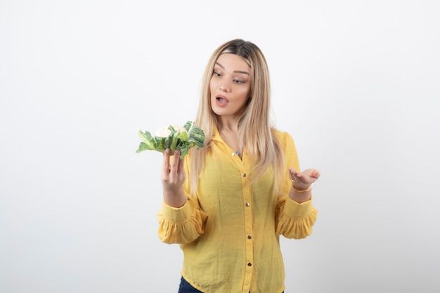 hübsches Frauenmodell, das Blumenkohl steht und betrachtet.