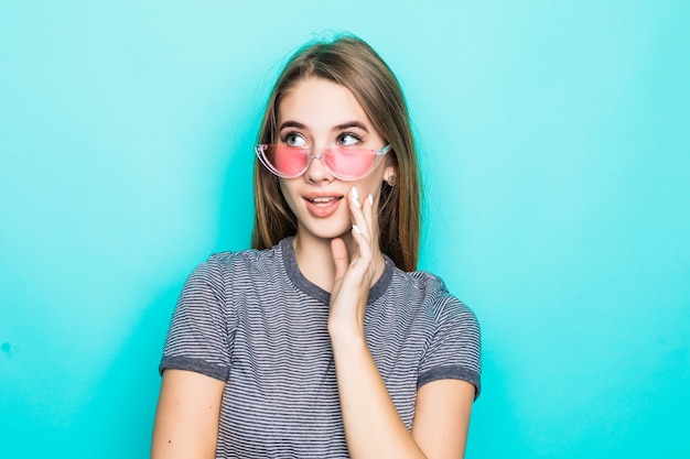 Hübsches geiles junges Modell im Mode-T-Shirt, im Hut und in der transparenten Brille lokalisiert auf grünem Hintergrund