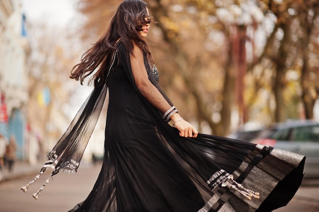 Hübsches indisches Mädchen im schwarzen Saree-Kleid posierte im Freien auf der Herbststraße