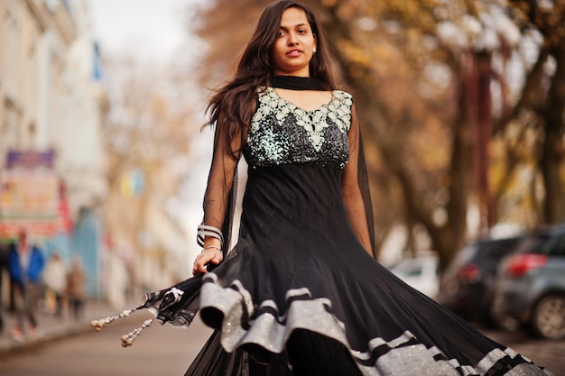 Hübsches indisches Mädchen im schwarzen Saree-Kleid posierte im Freien auf der Herbststraße