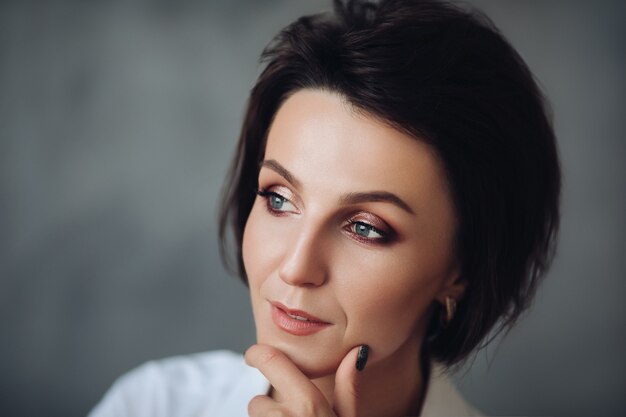 Hübsches kaukasisches weibliches Modell mit kurzen Haaren einzeln auf grauem Studiohintergrund
