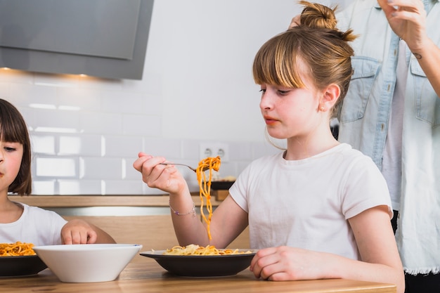 Hübsches Mädchen, das geschmackvolle Teigwaren in der Küche isst