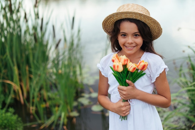 Hübsches Mädchen, das mittleren Schuss der Tulpen hält