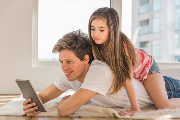 Hübsches Mädchen, das zurück auf ihrem Vater unter Verwendung des Handys sitzt