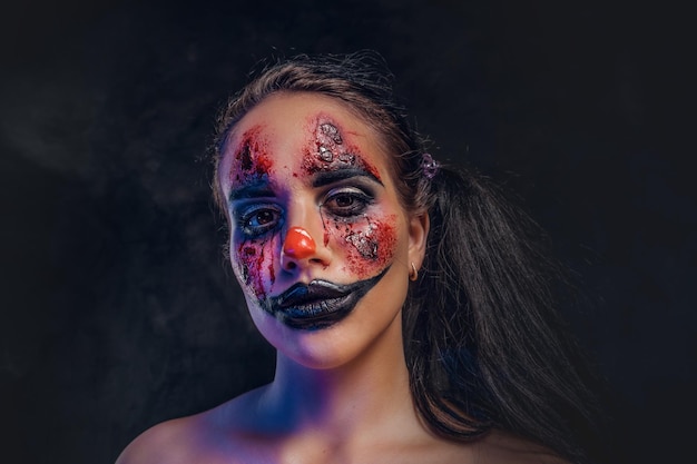 Hübsches Mädchen hat ein sehr gruseliges Make-up für Halloween in der Rolle eines gruseligen Clowns.