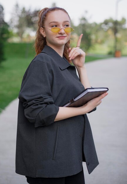 Hübsches Mädchen mit Sonnenbrille, das mit dem Finger nach oben zeigt