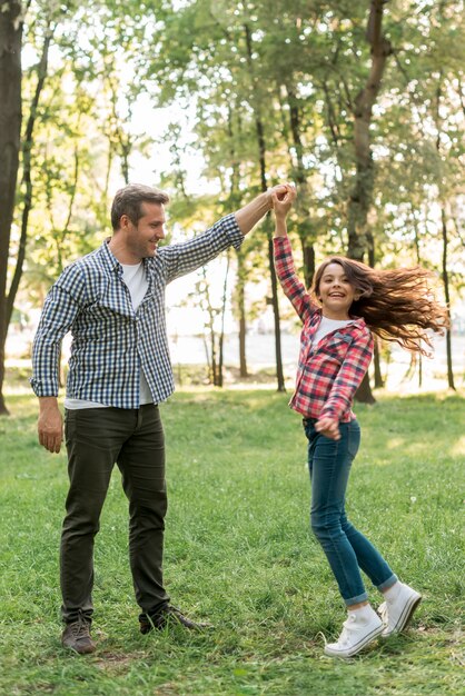 Hübsches Mädchentanzen mit ihrem Vater auf Grasland im Park