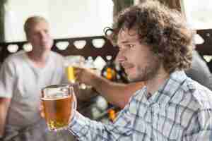 Kostenloses Foto hübsches männliches trinkendes bier nahe freunden in der stange