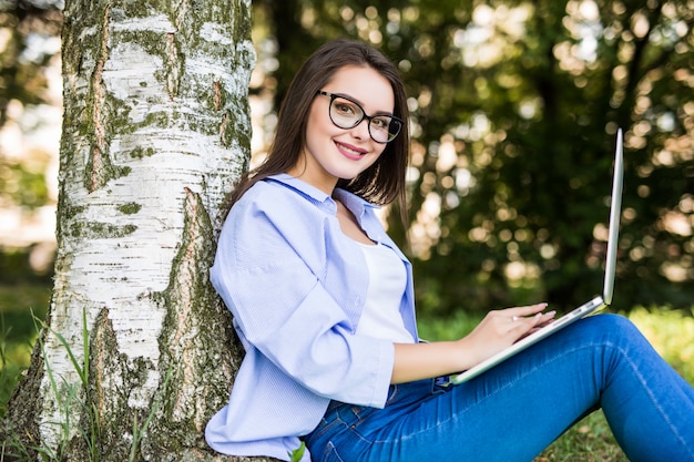 Hübsches Modell in Blue Jeans arbeiten mit Laptop im Stadtpark