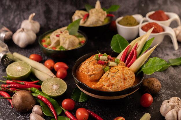 Hühnercurry in einer Schüssel mit Zitronengras, Kaffirlimettenblättern, Tomaten, Zitrone und Knoblauch