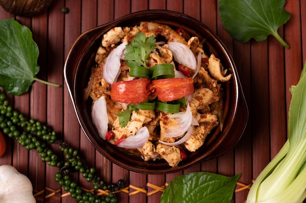 Hühnerlarb auf dem Teller Mit getrockneten Chilis, Tomaten, Frühlingszwiebeln und Salat