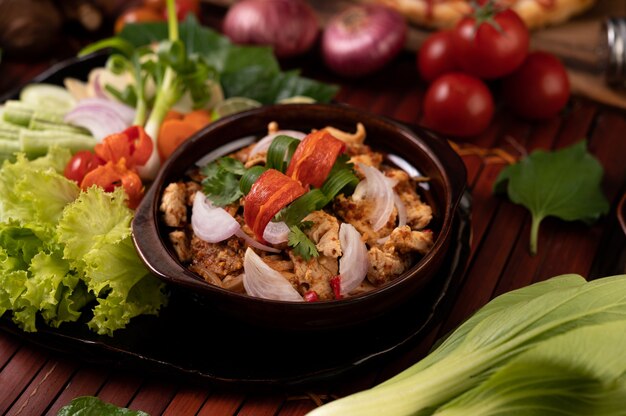 Hühnerlarb auf dem Teller Mit getrockneten Chilis, Tomaten, Frühlingszwiebeln und Salat