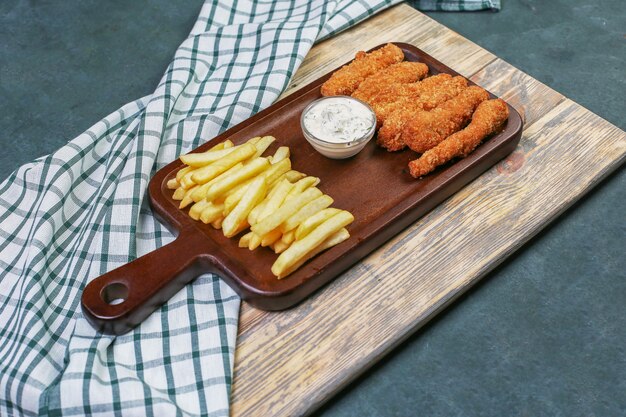 Hühnernuggets mit Pommes Frites und einem weißen Dressing.