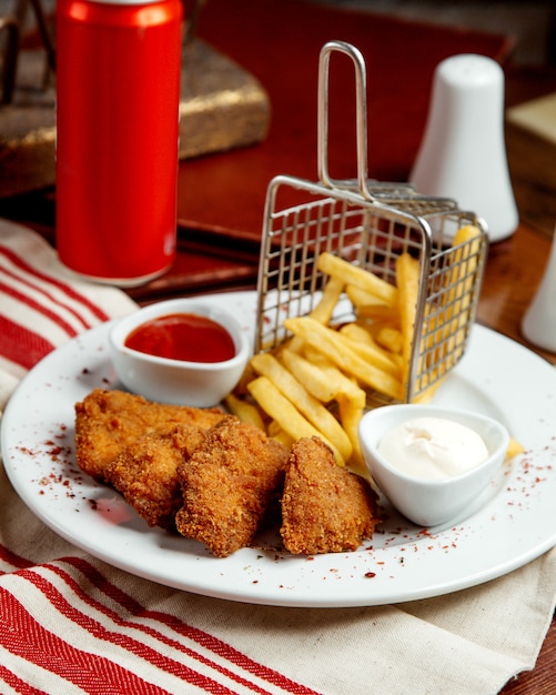 Hühnernuggets serviert mit Pommes Frites Mayonnaise und Ketchup