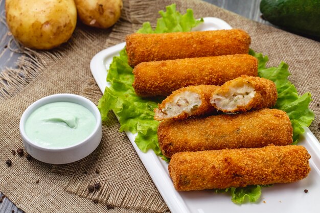 Hühnernuggets von der Seite auf Salat mit Sauce und ungeschälten Kartoffeln