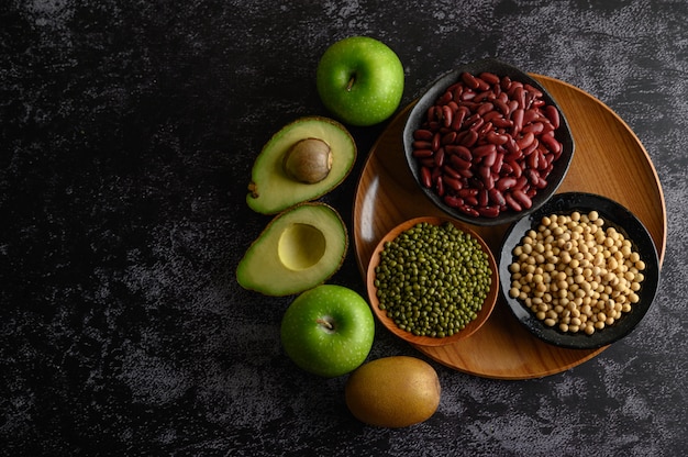 Kostenloses Foto hülsenfrüchte und obst auf einem schwarzen zementboden.