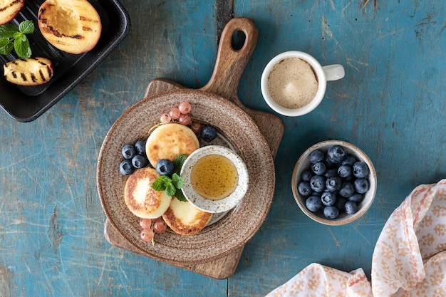 Kostenloses Foto hüttenkäse-pancakes mit frischen blaubeeren, johannisbeeren und pfirsichen auf einem teller