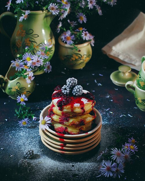 Hüttenkäsepfannkuchen, Syrniki, Quarkstückchen mit gefrorenen Beeren (Blackberry) und Puderzucker in einer Weinleseplatte. Gourmet-Frühstück