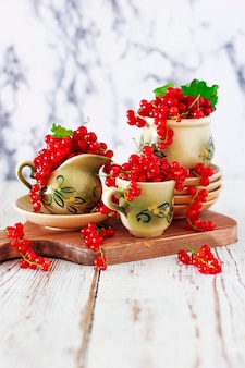 Hüttenkäseplätzchen rollt mit roten johannisbeeren auf keramischer platte mit keramischem tee- oder kaffeesatz der weinlese, teezeit, frühstück, sommerbonbons
