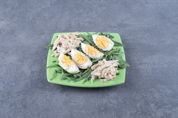 Huhn mit gekochten Eiern auf grüner Platte.