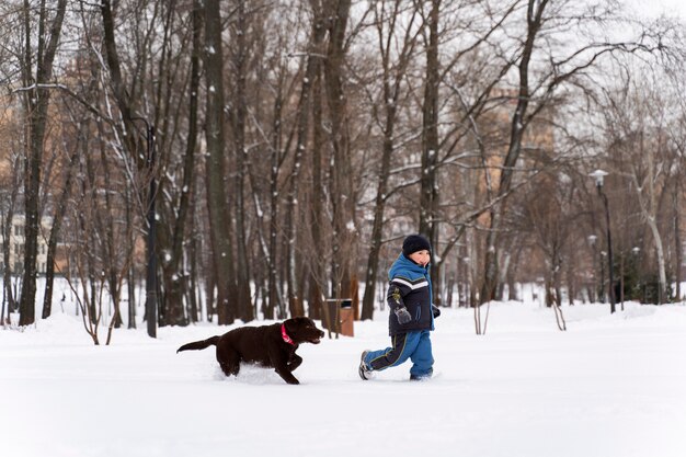 Hund spielt mit Kind im Schnee mit der Familie