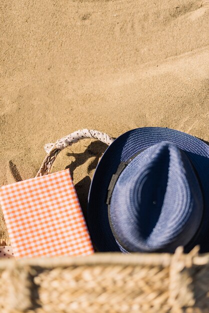 Hut, Korb und Tagebuch auf dem Sand