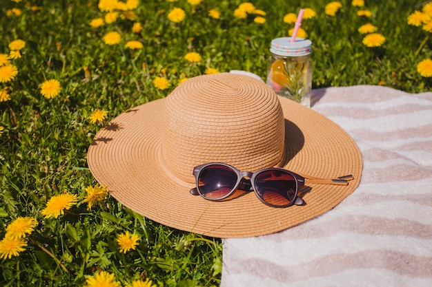 Hut und Sonnenbrille auf dem Gras mit gelben Blüten