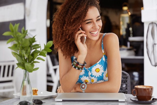 Ich bin froh, dass eine hübsche dunkelhäutige Frau mit Tarifen auf Mobiltelefongesprächen zufrieden ist, lacht freudig, während sie über etwas Angenehmes spricht