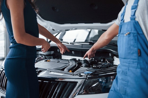 Ich denke dein Problem in diesem Teil. Frau im Autosalon mit dem Angestellten in der blauen Uniform, die ihr repariertes Auto zurücknimmt