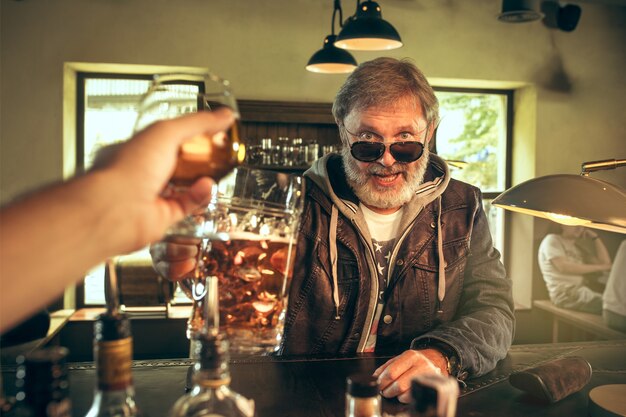 Ich genieße meinen Lieblingsbrot und mein Lieblingsbier. Mann mit Bierkrug, der am Tisch sitzt.