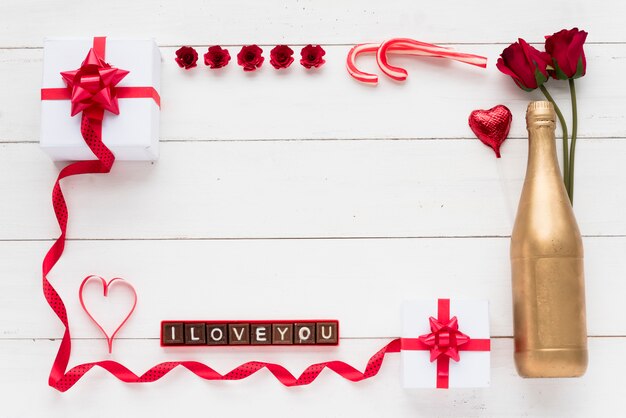 Ich liebe dich Inschrift auf Schokoladenstücken in der Nähe von Geschenken, Blumen und Flaschen