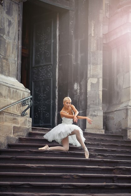 Ich liebe es, sie tanzen zu sehen. Weichzeichneraufnahme einer Ballerina, die auf ihrem Knie posiert, die auf der Treppe eines alten Gebäudes steht