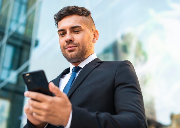 Im Freien erfolgreicher Geschäftsmann, der das Telefon betrachtet