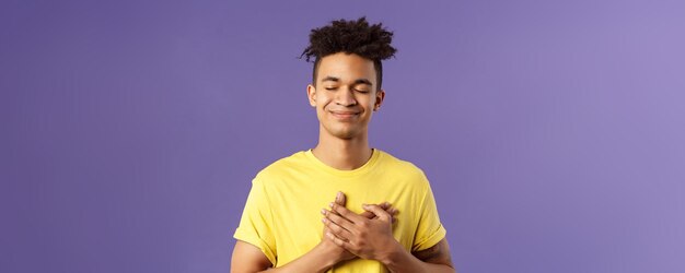 Immer in meinem Herzen berührt sorglos hübscher junger Mann mit Dreads gelbes T-Shirt Augen schließen und lächeln