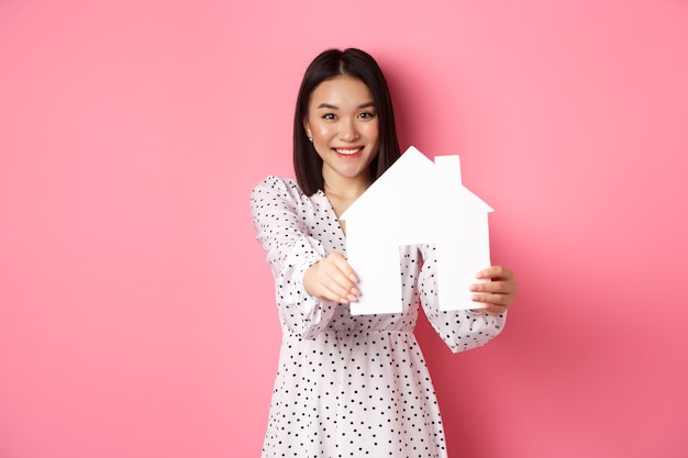 Immobilien erwachsene asiatische Frau auf der Suche nach Haus mit Hausmodell und lächelnder Promo von Maklercom ...