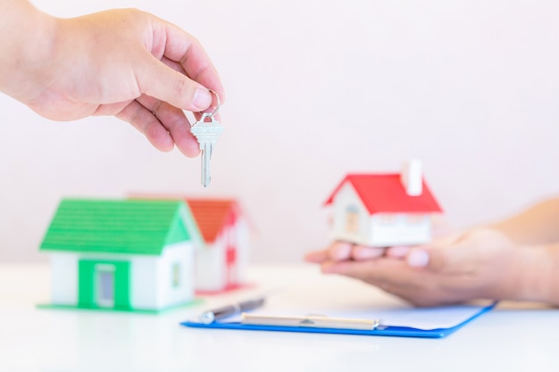 Immobilienmakler mit Hausmodell und Schlüsseln