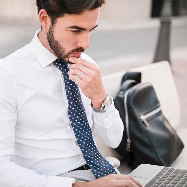 In Betracht gezogener junger Mann, der Laptop verwendet