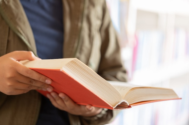 In der Bibliothek - Teenager-Studentin mit Büchern liest in einer High-School-Bibliothek.