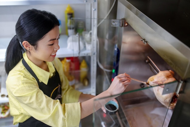 In der Küche. Asiatisches junges Mädchen, das in der Küche arbeitet und Essen zubereitet