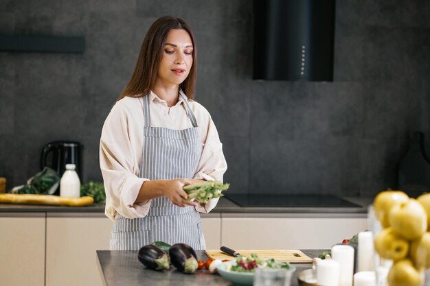 In der Küche. Langhaarige junge Frau, die das Mittagessen in der Küche zubereitet