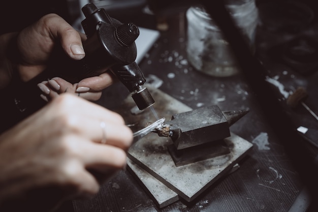 In der Werkstatt ist eine Juwelierin damit beschäftigt, Schmuck zu löten