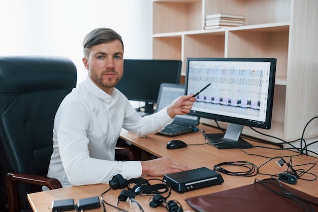 Kostenloses Foto in die kamera schauen. der polygraph-prüfer arbeitet im büro mit der ausrüstung seines lügendetektors