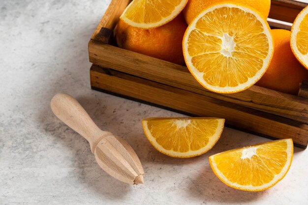 In Scheiben geschnittene frische Orangen mit Holzreibahle auf Marmor.