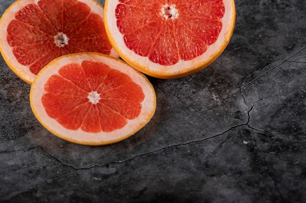 In Scheiben geschnittene saftige frische Grapefruit auf einem dunklen Tisch